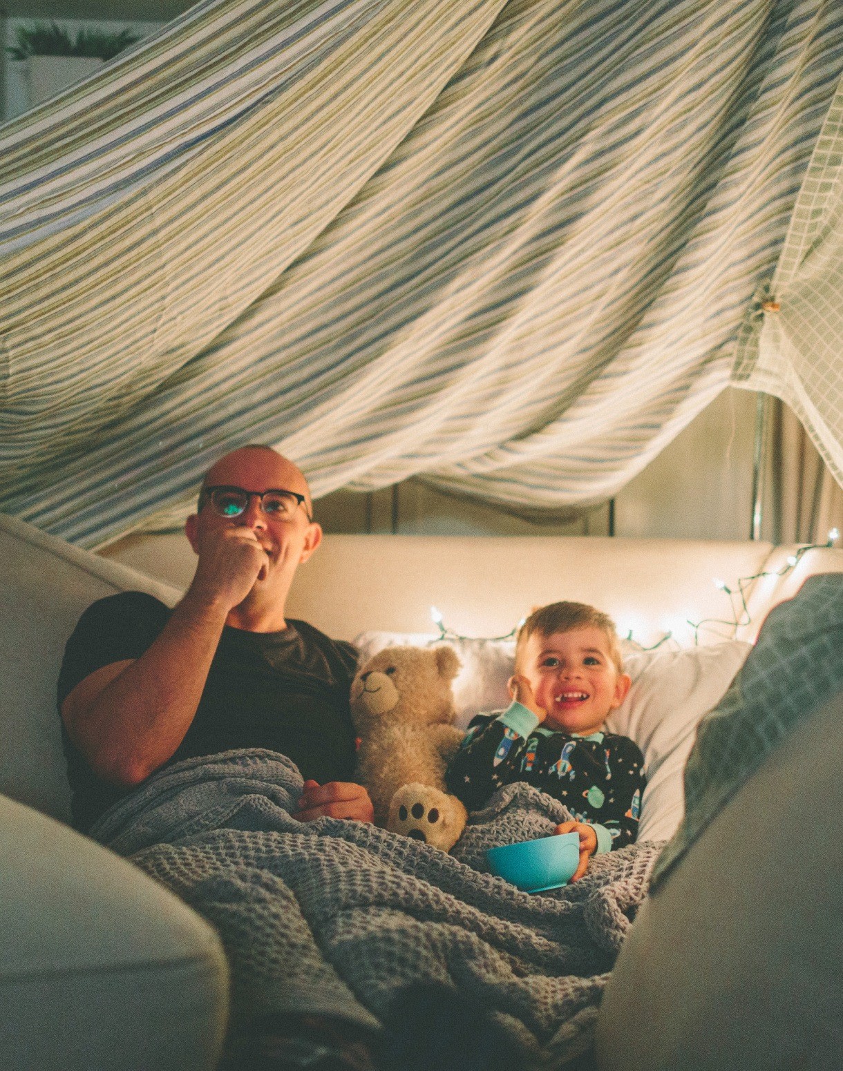 A man and a child in a blanket fort